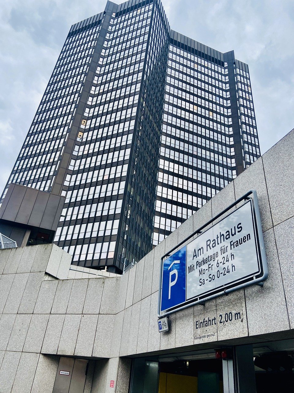 a sign on a wall with a tall building in the background